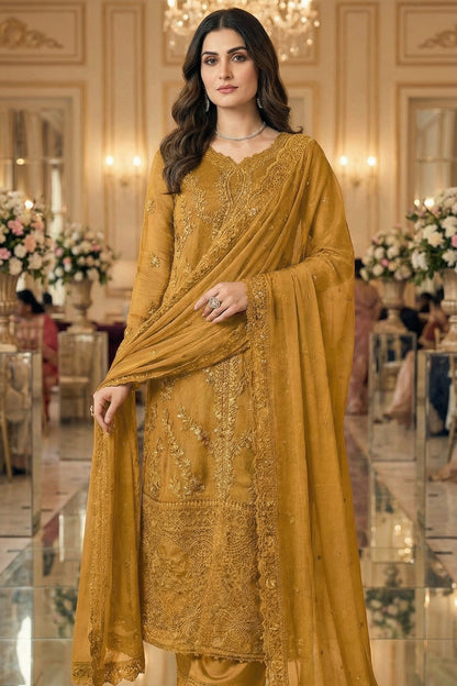 Woman in a mustard yellow embroidered outfit standing in an elegant interior setting.