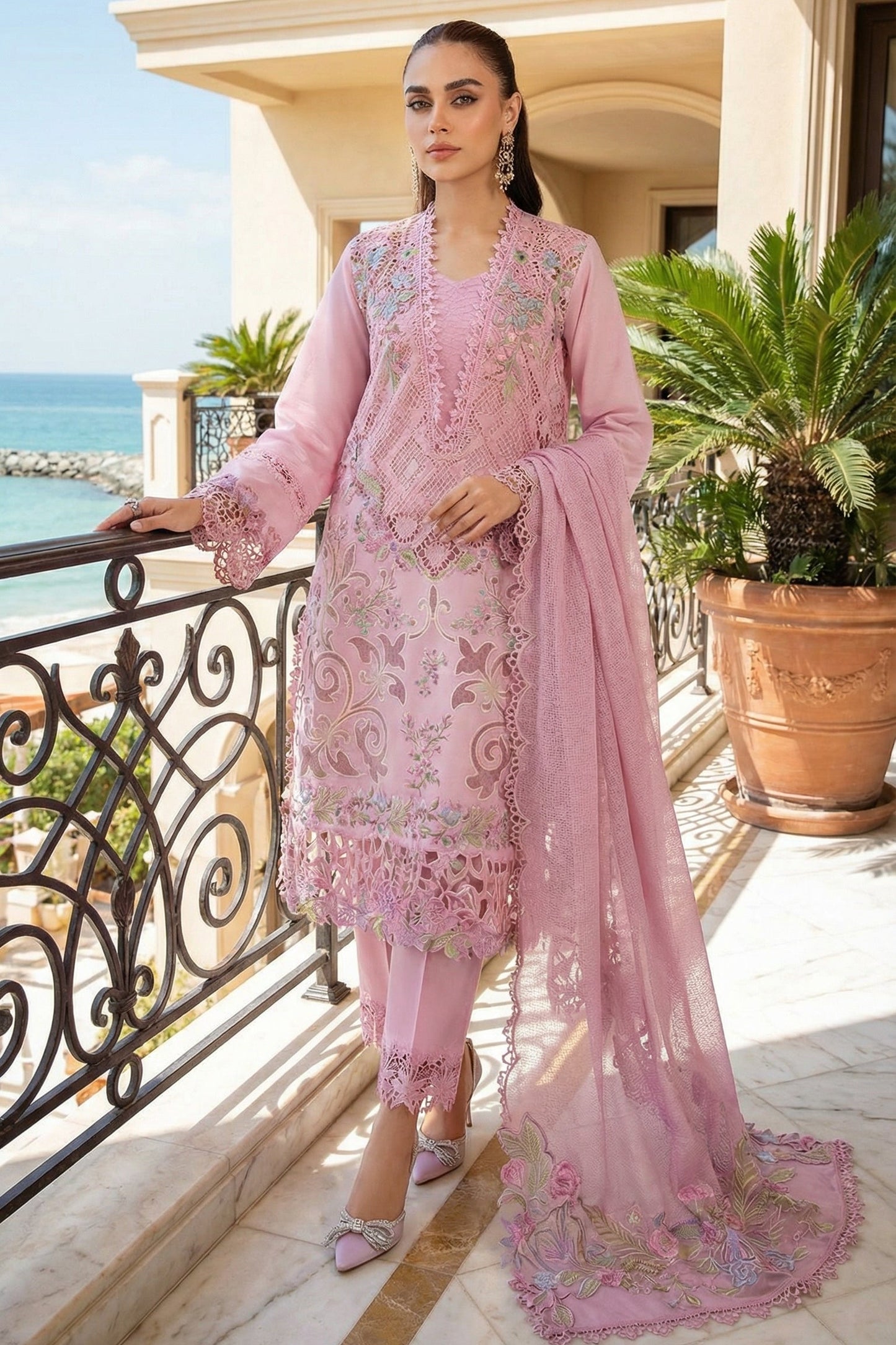 Woman in a pink embroidered outfit standing on a balcony with ocean view